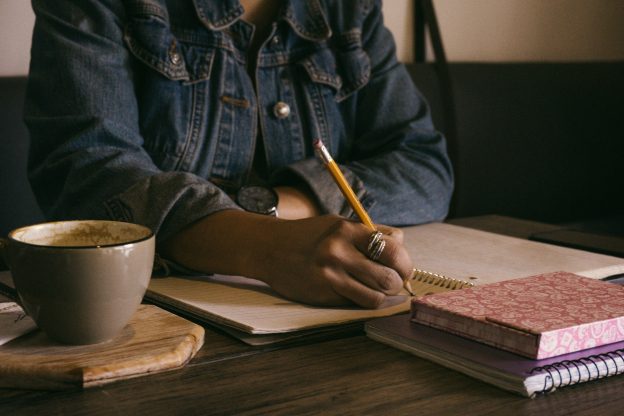 writing at a desk with hot drink