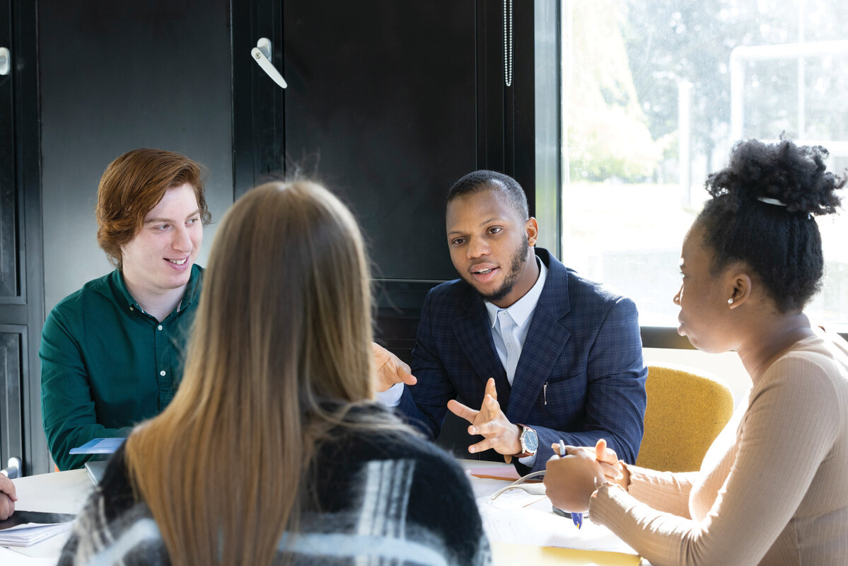Four students sitting chatting at table