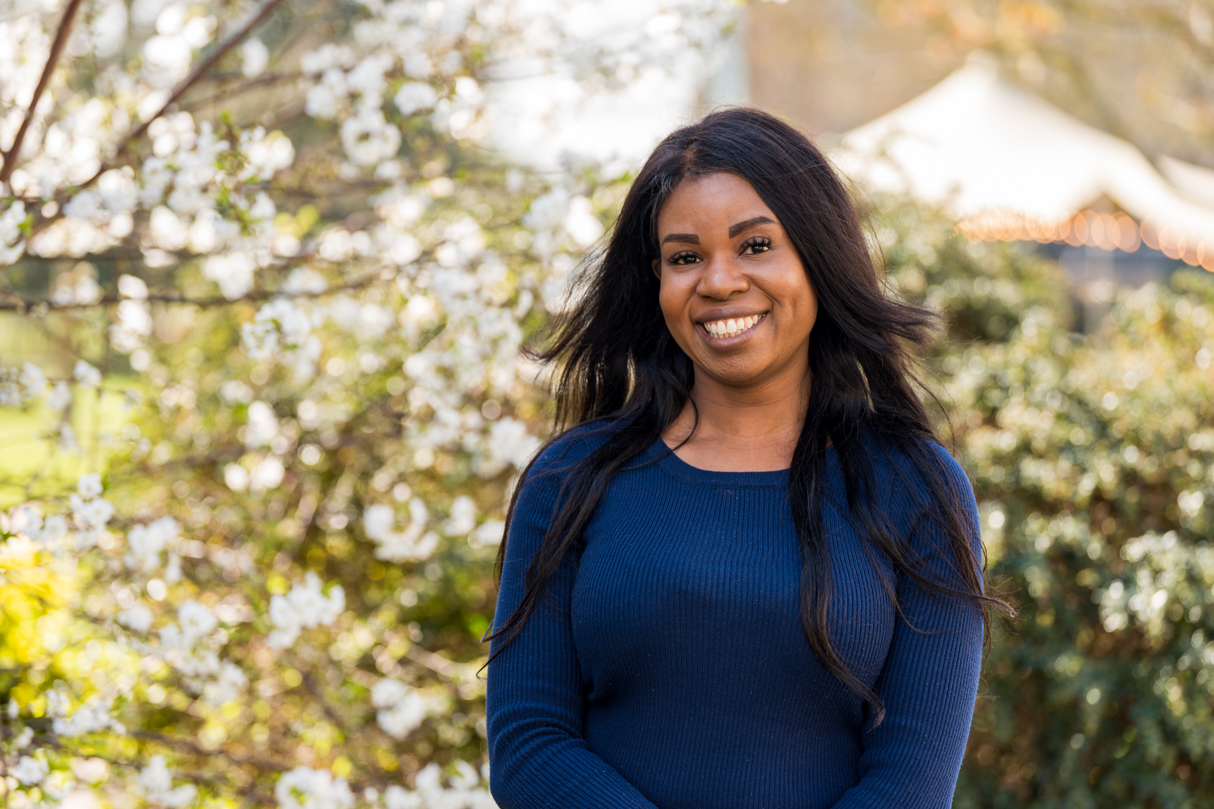 Student Toyin smiling next to blossom tree